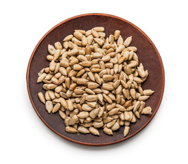 Plate with peeled sunflower seeds on white background