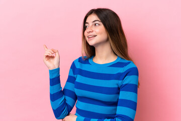 Young caucasian woman isolated on pink background pointing finger to the side