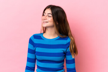 Young caucasian woman isolated on pink background looking to the side and smiling