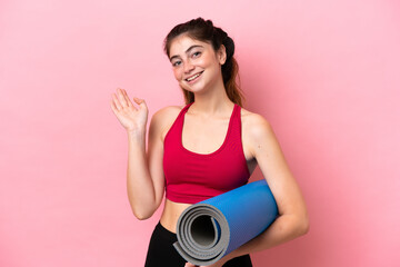 Young sport woman going to yoga classes while holding a mat extending hands to the side for...