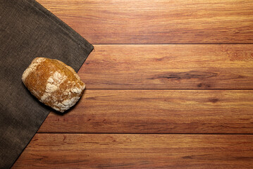 Homemade wholemeal bread rolls on a gray dishcloth. Light wooden table background, top view and space for text.