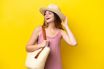 Young caucasian woman holding a beach bag isolated on yellow background smiling a lot