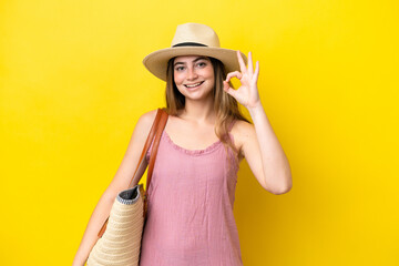 Young caucasian woman holding a beach bag isolated on yellow background showing ok sign with fingers