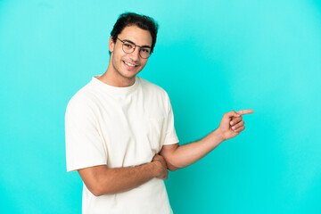 Caucasian handsome man over isolated blue background pointing finger to the side