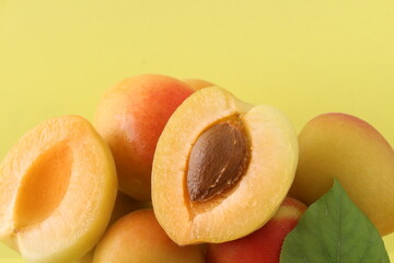 Close up on apricot with green leaf isolated on yellow background. Cut fruit with detail.