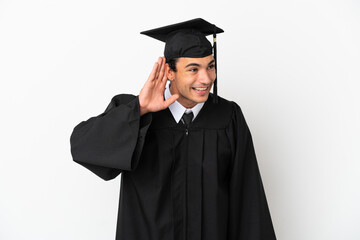 Young university graduate over isolated white background listening to something by putting hand on the ear
