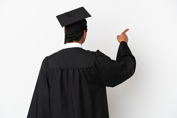 Young university graduate over isolated white background pointing back with the index finger