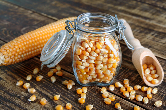 Corn grains in a glass jar on a wooden background. Maize for popcorn