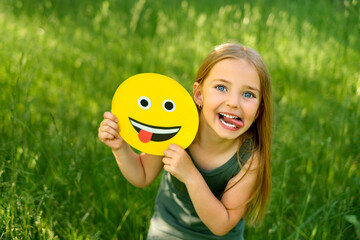 Funny bully girl shows tongue holding a fun humorous smile face in hands. Happy naughty emotional...