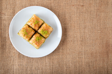 Pistachio baklava on a white plate.A plate baklava on fabric background