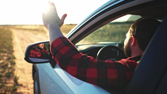 Man of a car while driving. Tourist puts her hand out of window to feel the breeze at sunset. Free man hand out of the window rides a car at sun glare. Car travelling adventure male. Freedom concept.