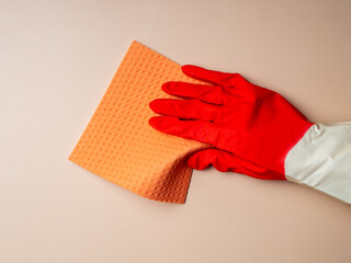 Woman in rubber glove holding sponge on beige background with copy space