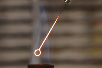 Close-up detail of an inoculation loop being sterilized with a Bunsen burner before being used in bacterial cultures. Medicine and microbiology concept