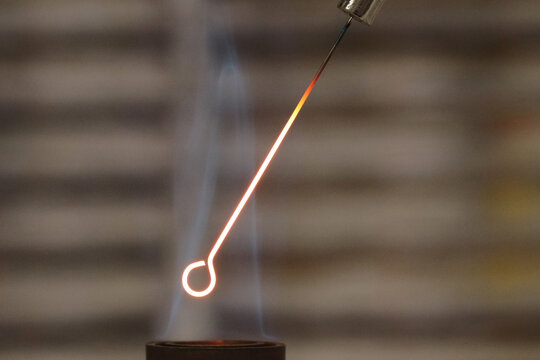 Close-up detail of an inoculation loop being sterilized with a Bunsen burner before being used in bacterial cultures. Medicine and microbiology concept