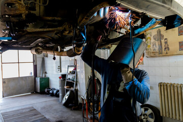 Skilled welder with mask doing the welding in a workshop.During the welding, there were a lot of...