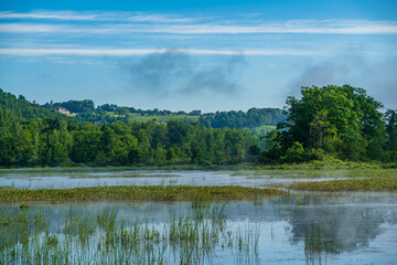 Fototapeta premium Landscape in the mountains with pond, forest and morning fog