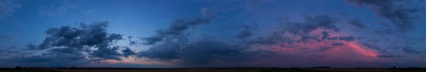 A wide majestic view of a panoramic dark sunset over the fields.