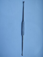 Volkmann's bone metal spoon lies on a blue surface in a hospital