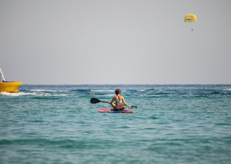 A girl with an oar floats on a board on the sea