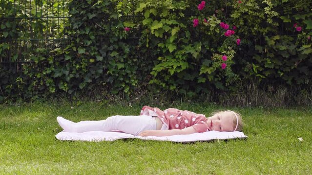 Little Girl Doing Yoga Exercises In park. The baby does exercises on the grass. The right sporting childhood.  little girl doing exercises in the park. 