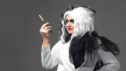 Obraz premium A fatal beauty in a daring fashion image with black and white hair. A rebellious stylish image for Halloween. a young woman in a black and white outfit smokes a cigarette using a mouthpiece