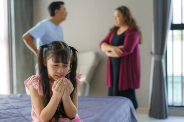 Family violence and family conflict concept, sad little girl with blur of mother fighting father with quarrel at home.