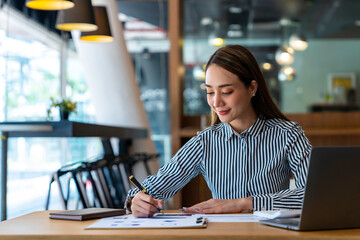 Portrait of beautiful asian woman working financial report with laptop computer at office.