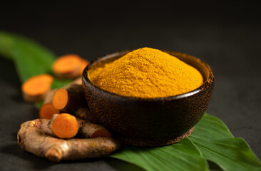  Turmeric powder and fresh turmeric (curcumin) on a black background, copy space.
