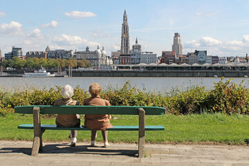  Pareja de señoras mayores sentadas en un banco mirando la ciudad de Amberes
