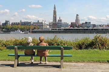 Fotobehang Paar oudere dames zittend op een bankje kijkend naar de stad Antwerpen © Sheila