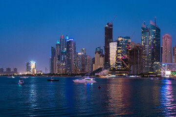 View of the skyline of Marina Dubai at night in winter with boats and yachts
