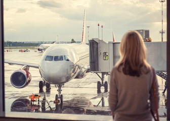 silhouette of a woman at the airport at the window against the background of a Russian airline plane
