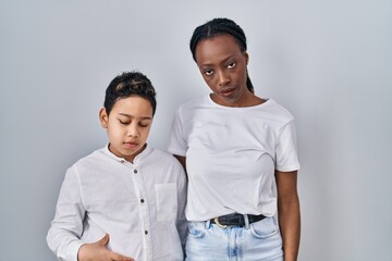 Young mother and son standing together over white background looking sleepy and tired, exhausted for fatigue and hangover, lazy eyes in the morning.