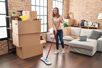 Young woman smiling confident cleaning floor at new home