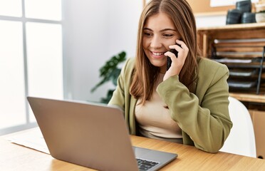 Young hispanic woman talking on the smartphone working at office