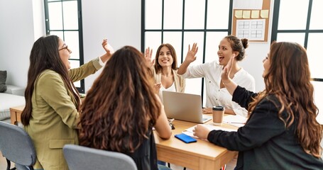 Group of businesswomen smiling happy celebrating high five at the office.