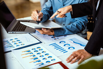 Obraz premium Two business people sit down to analyze financial data from earnings graphs showing the company's earnings to be presented at a meeting.