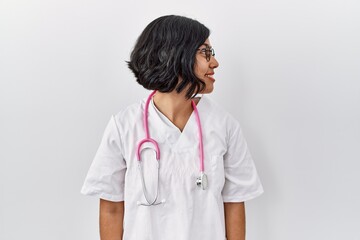 Young hispanic doctor woman wearing stethoscope over isolated background looking to side, relax...