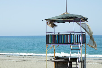 Lifeguard tower at the beach in the background blue sea and sky.