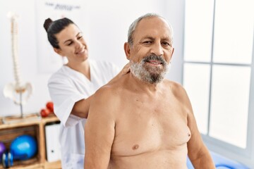 Physiotherapist and patient smiling confident having rehab session at clinic