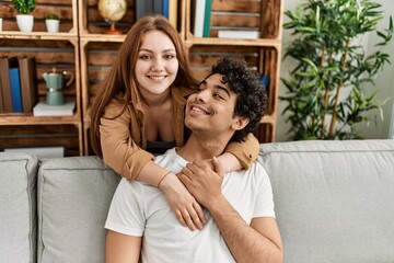 Young couple smiling happy and hugging sitting on the sofa at home.