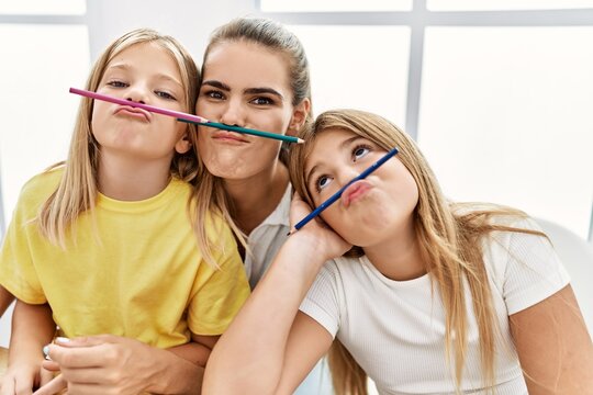 Mother and daughters with funny expression drawing at home
