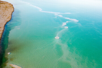 Israeli coast of the Dead Sea. salt mushroom  crystals formations, clear cyan green calm water near, typical landscape at Ein Bokek beach, Israel