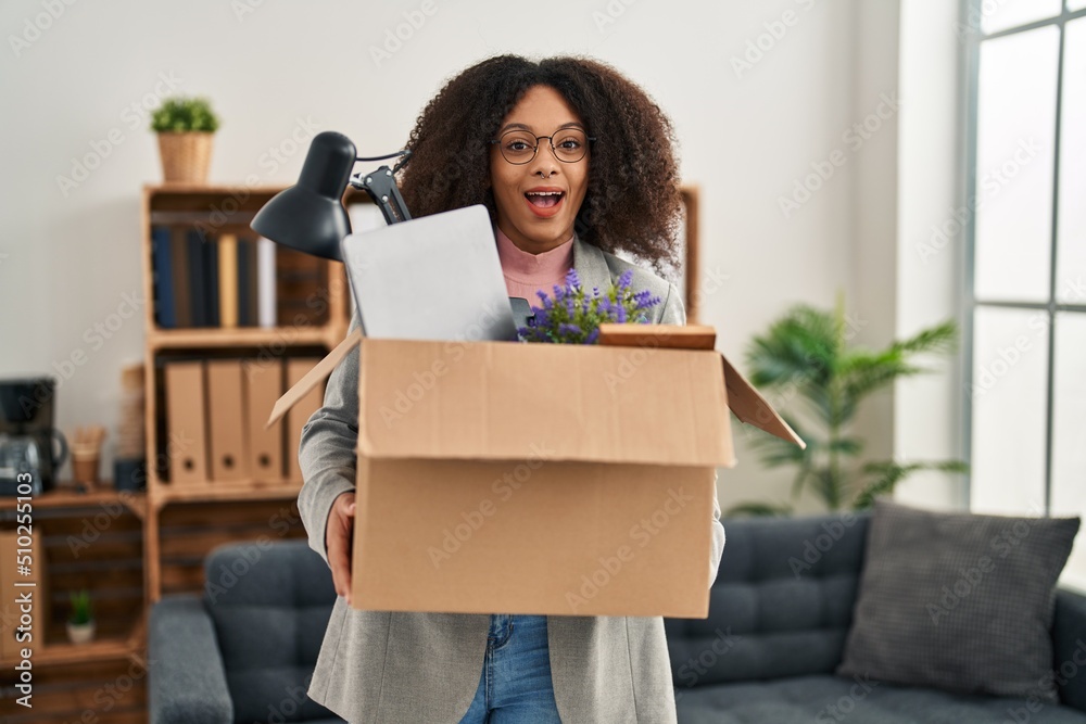 Sticker Young african american woman moving to a new office holding box with items celebrating crazy and amazed for success with open eyes screaming excited.