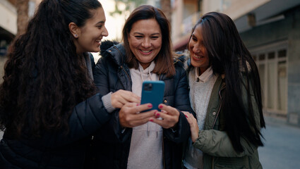 Mother and daugthers using smartphone standing together at street
