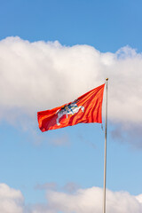 Vertical photo of historical Lithuanian red flag with Vytautas the great figure against sky background. flag with an armour-clad knight on horseback holding a sword and shield.