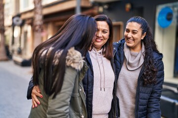 Three woman mother and daughters hugging each other at street