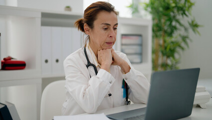 Middle age hispanic woman wearing doctor uniform stressed working at clinic