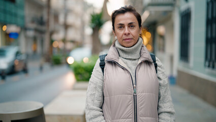 Middle age hispanic woman with relaxed expression standing at street