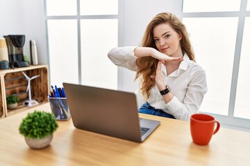 Young caucasian woman working at the office using computer laptop doing time out gesture with...